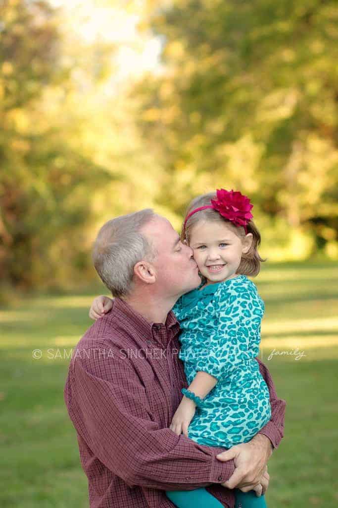 father kisses daughter on the cheek