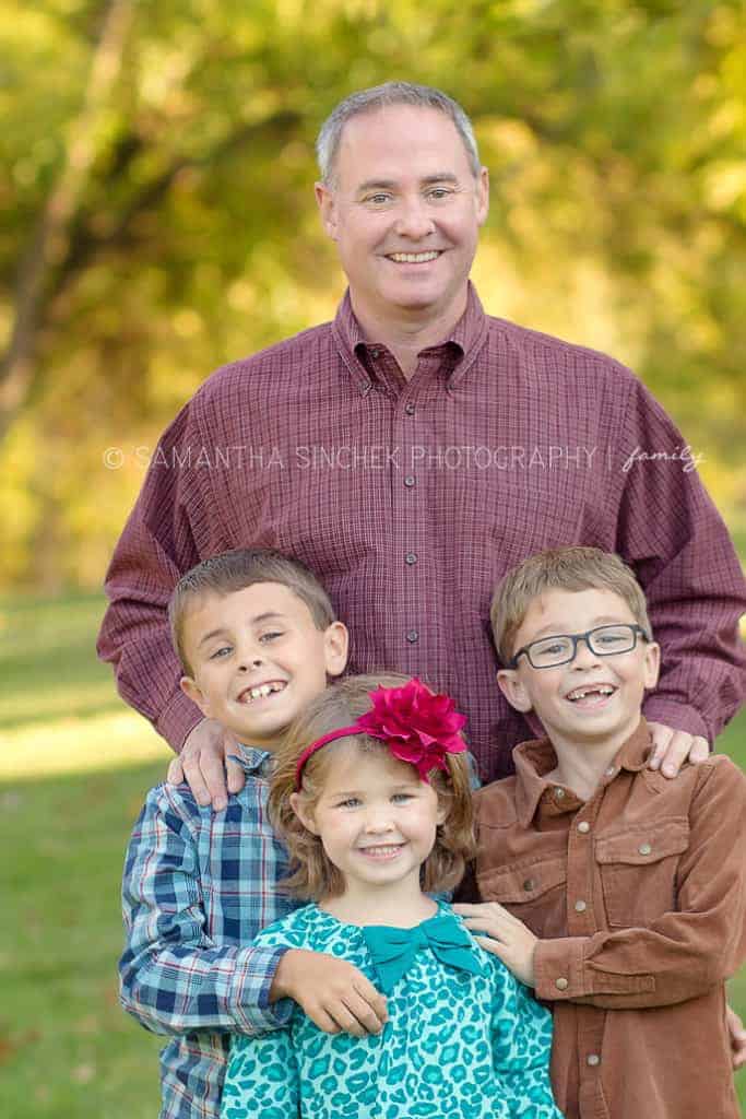 children poses for a photo with their father 