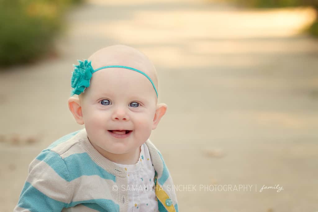 toddler girl sits on path wearing headbamd