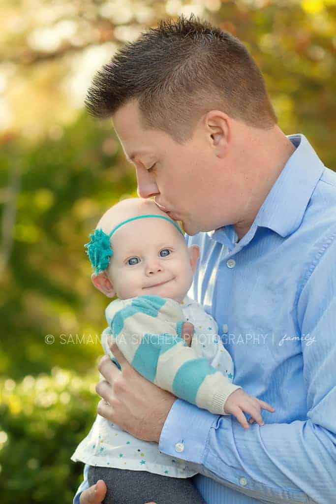 father kisses toddler girl on head at family session with samantha sinchek 