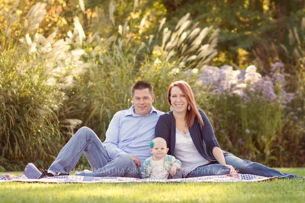 family sits on grass at ault park