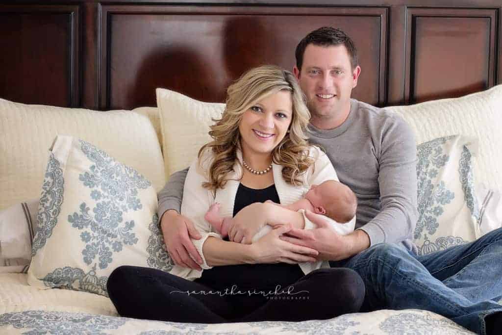 mother and father hold newborn daughter in their bedroom