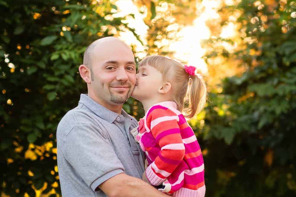 Young daughter kisses dad on the cheek