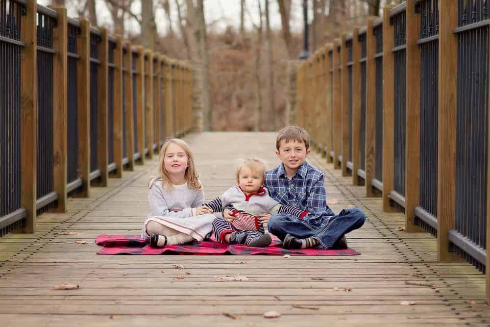 three siblings sit together during family photo session at SHARON woods, CINCINNATI