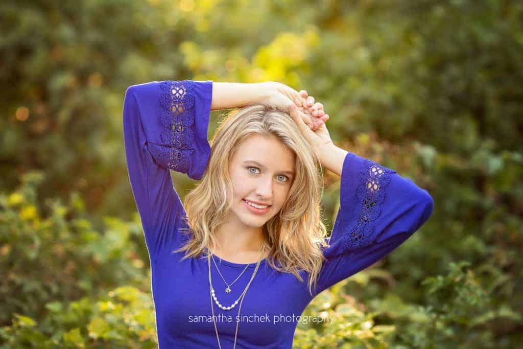 senior girl from kings high school wears blue dress with hands above her head