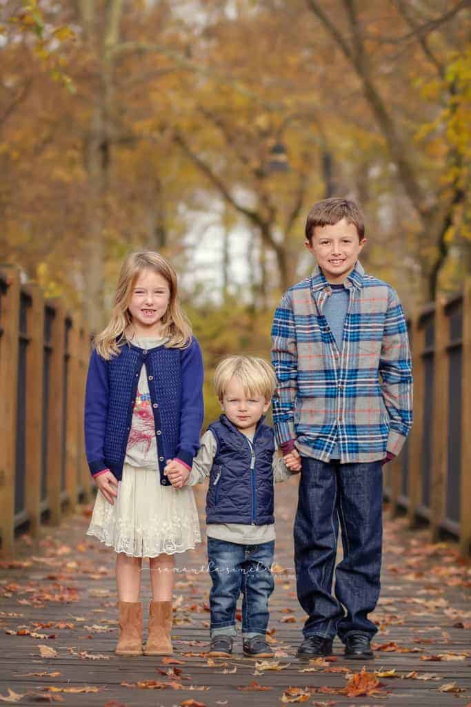 Three siblings hold hands during fall pictures at Sharon Woods