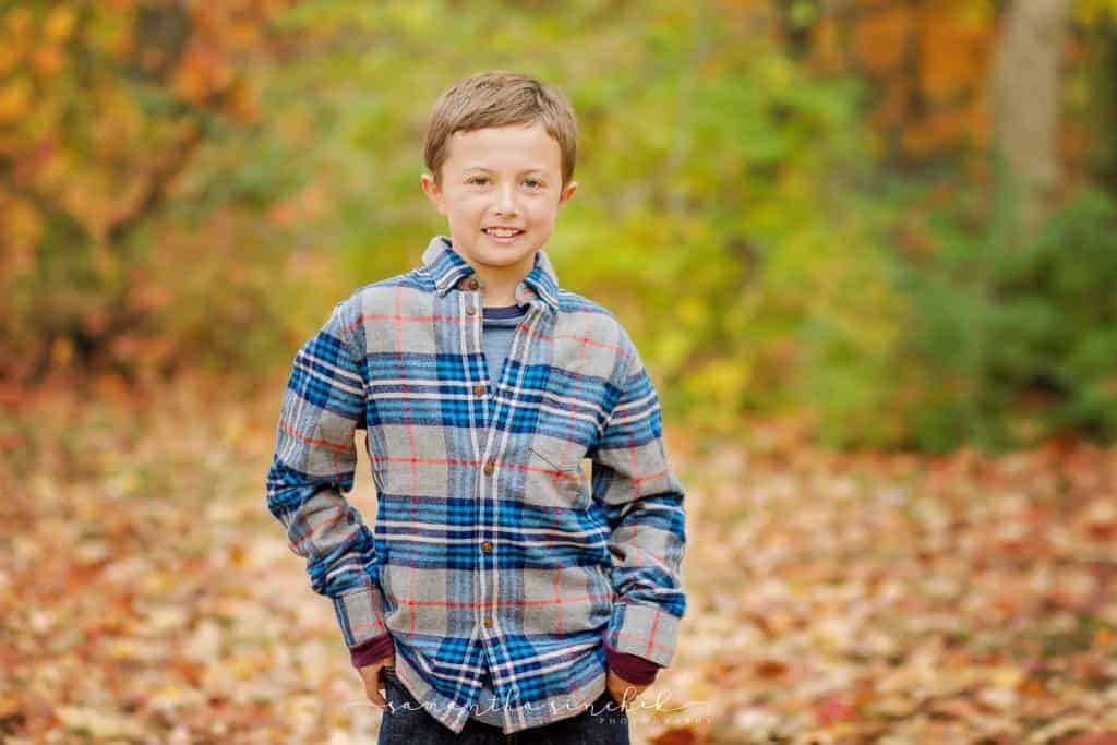 boy wearing plaid shirt smiles at camera