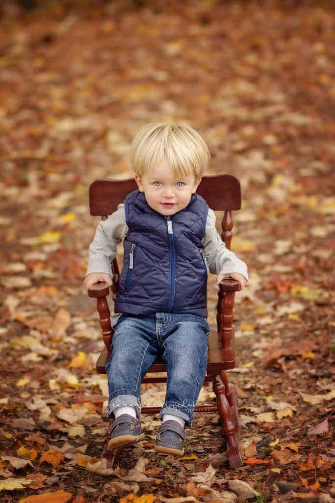 little boy sits in a rocking chair during pictures