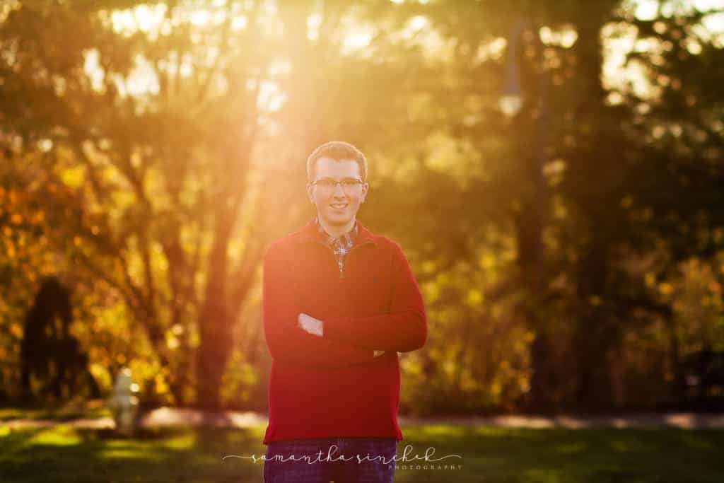 high school senior boy stands with arms crossed at ault park
