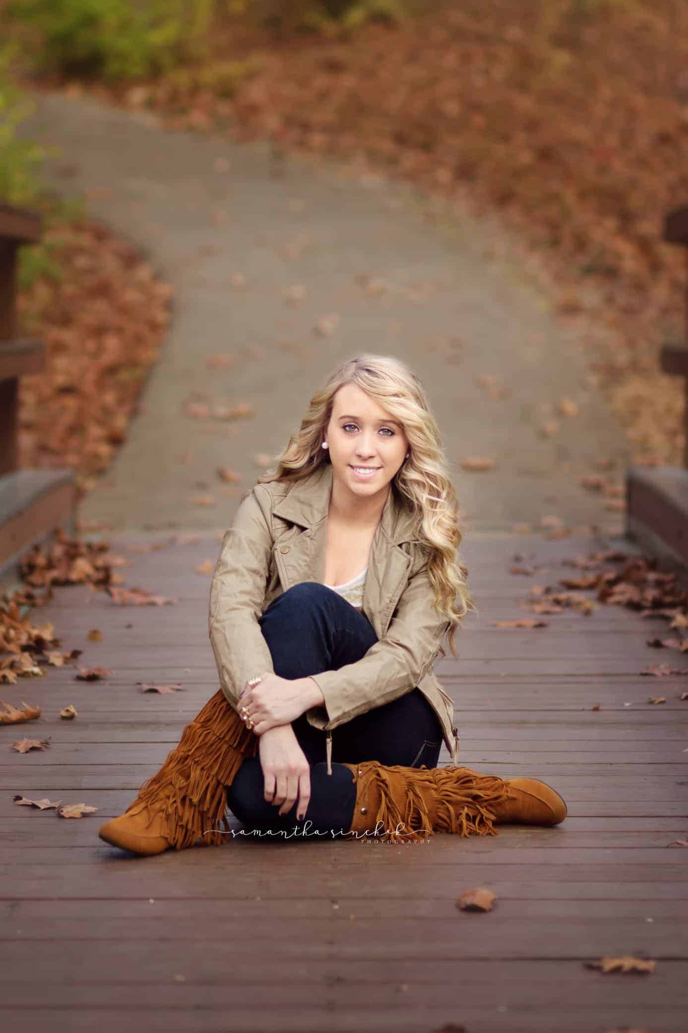 teen sits on bridge during senior photos in cincinnati