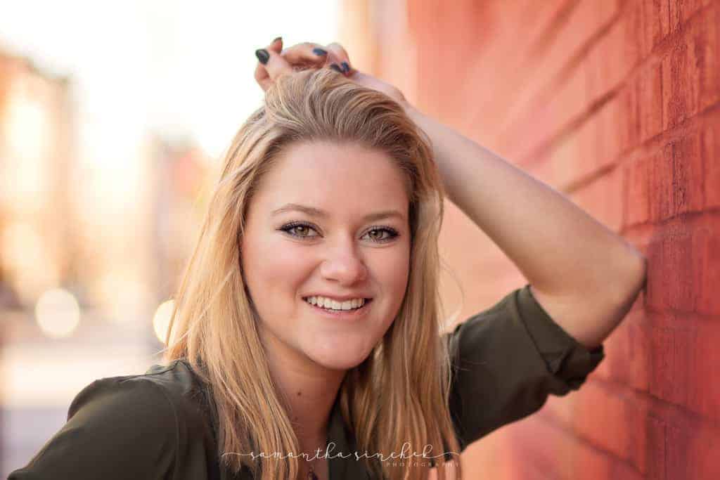 Mason senior girl leans against brick wall in OTR Cincinnati