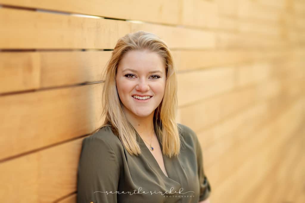 Cincinnati senior girl poses against wood wall in OTR