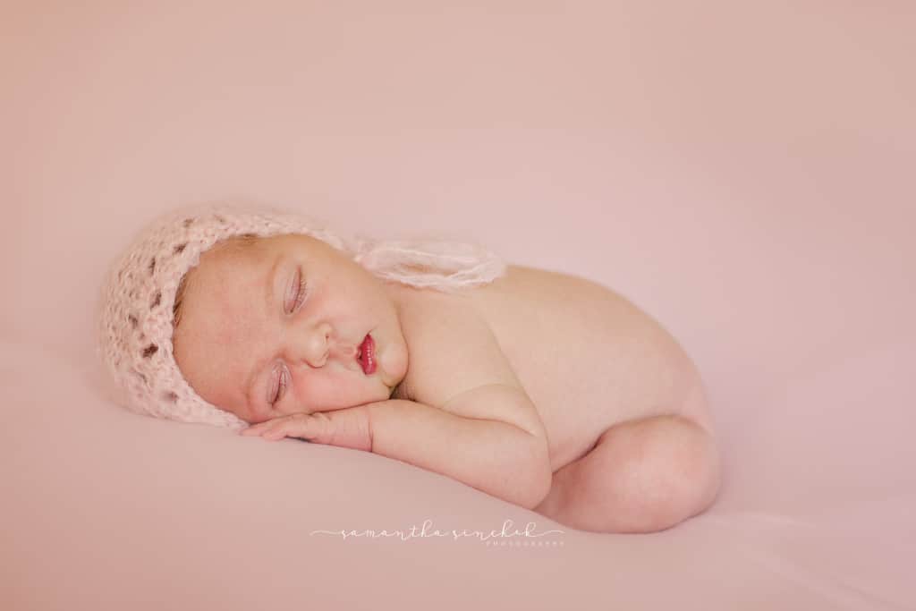 Cincinnati newborn girl sleeps on pink wearing pink bonnet
