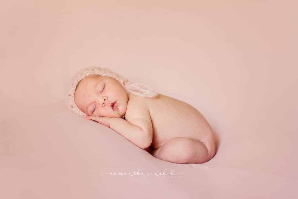 Cincinnati newborn girl sleeps on pink wearing pink bonnet