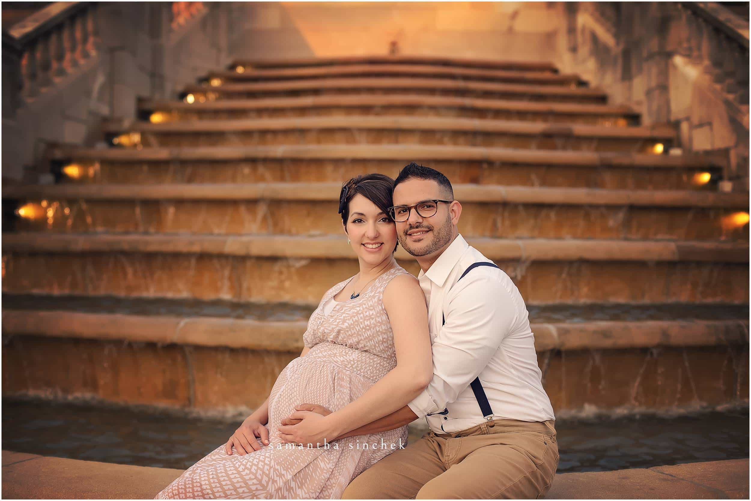 COUPLE SITS ON FOUNTAIN IN FRONT OF AULT PARK PAVILION