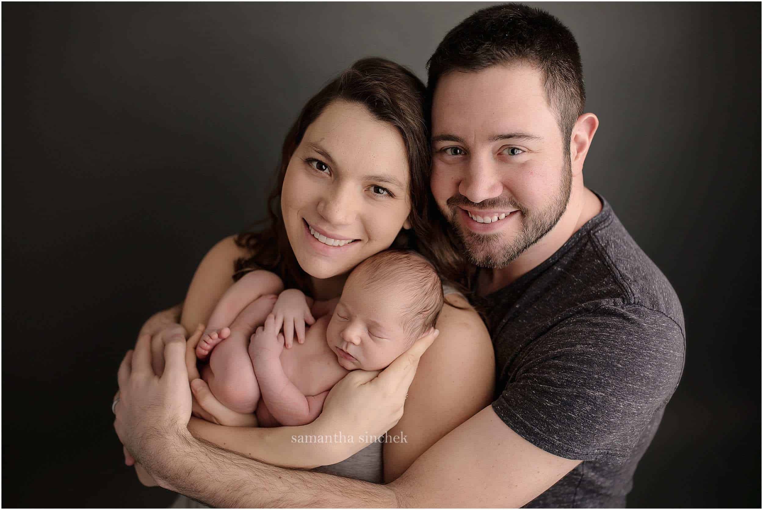 young family holds newborn son at pictures with Cincinnatis premier newborn photographer Samantha sinchek