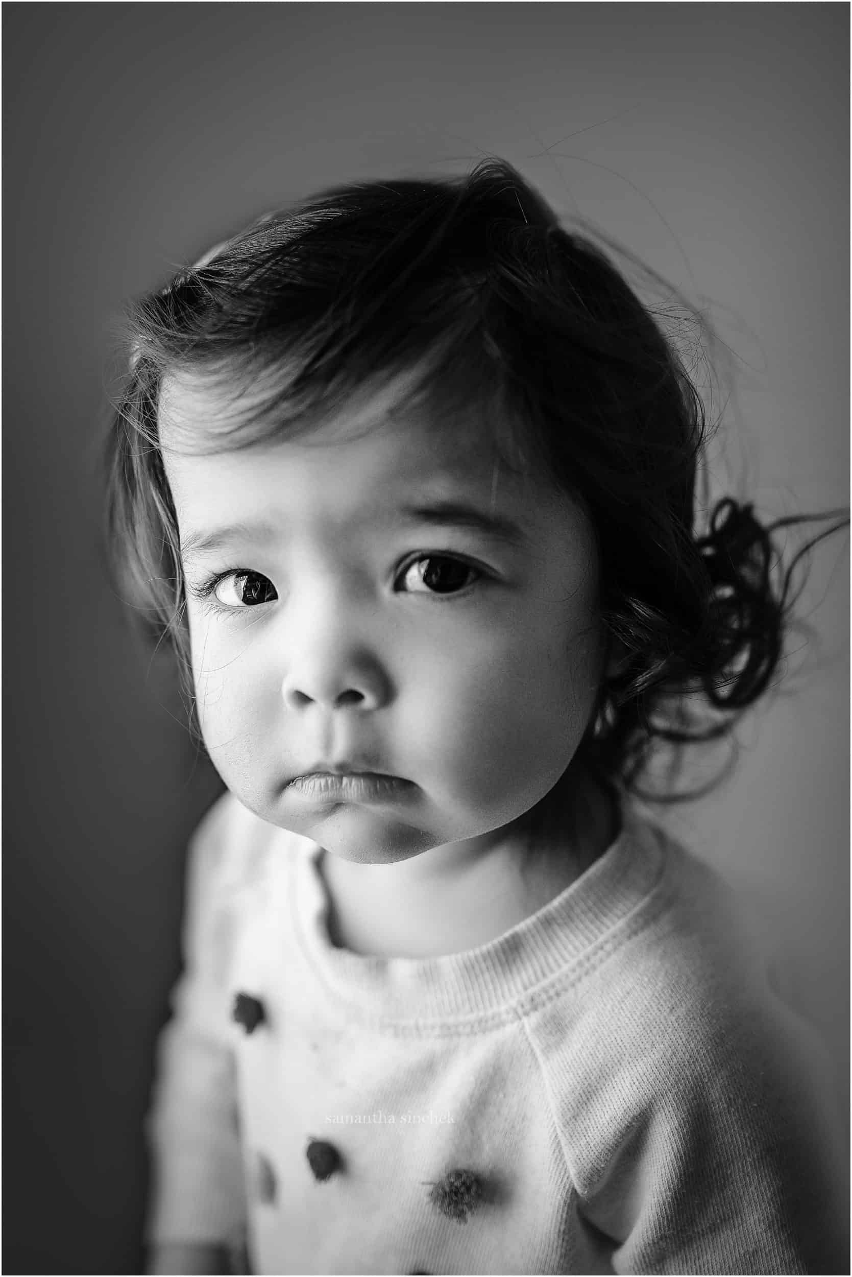 two year old stares at camera during newborn pictures for her sister