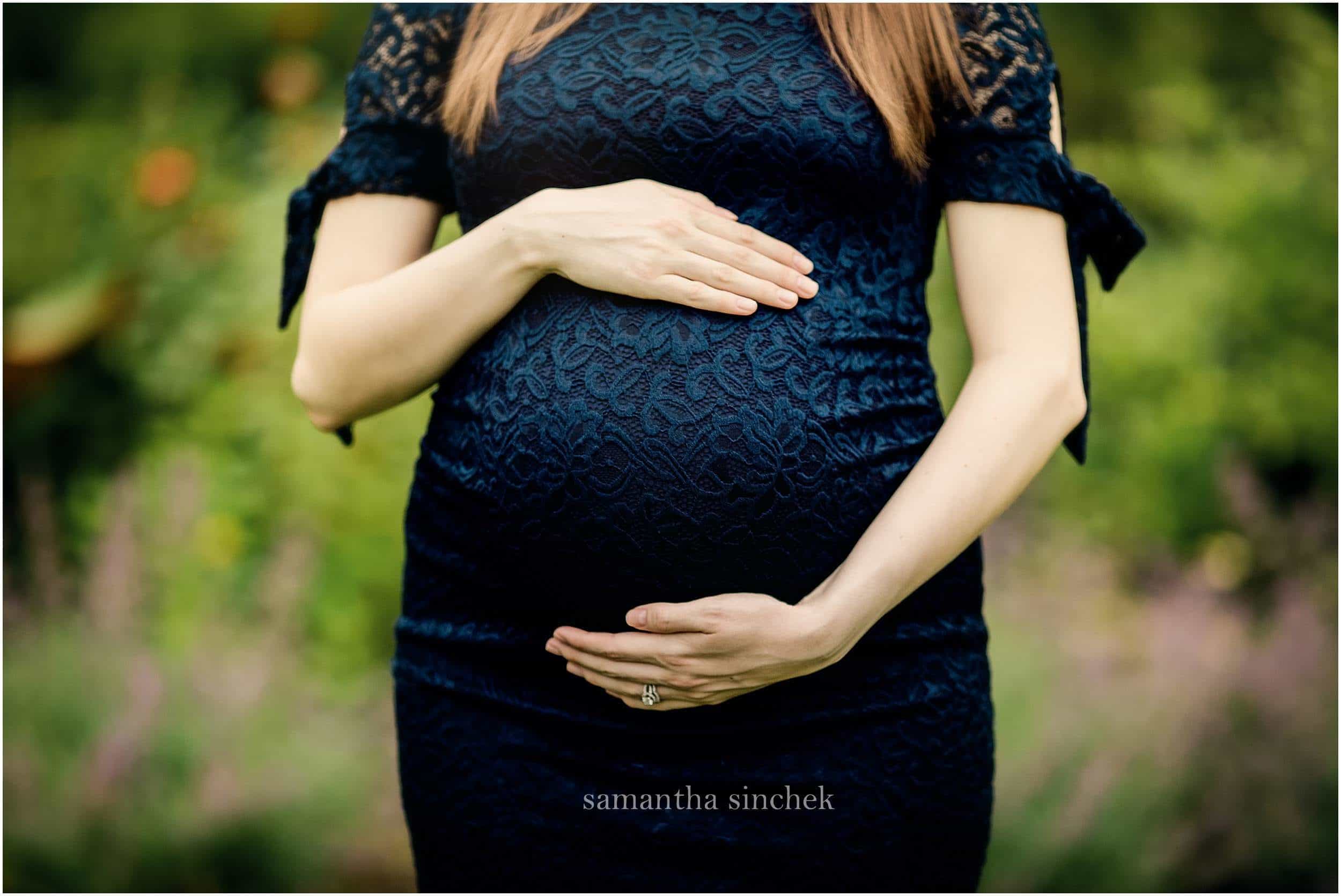 mother holding belly at Ault Park Cincinnati Ohio wearing blue dress