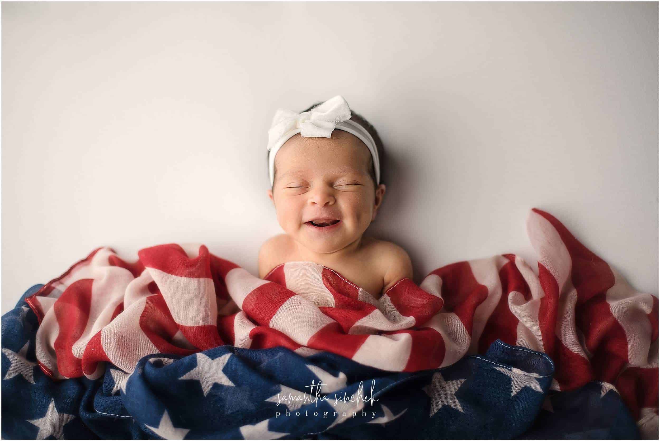 newborn smiles posing with American flag scarf with cincinnati newborn photographer Sinchek