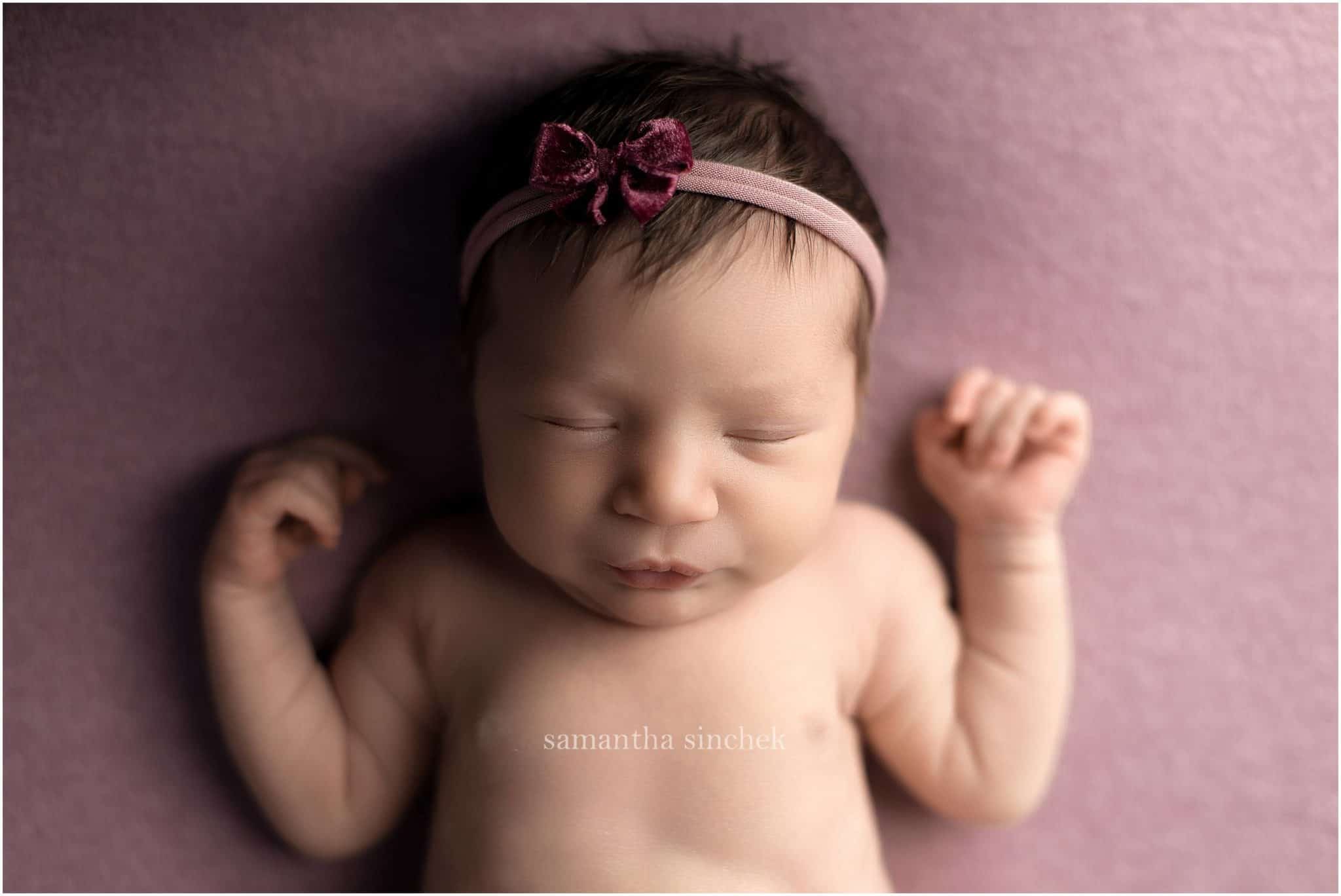baby girl asleep on purple background with cincinnati newborn photographer Samantha Sinchek